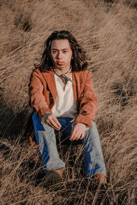 Portrait of young man sitting on grassy field