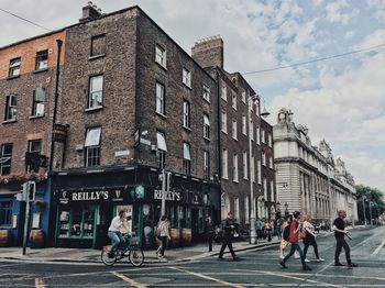 People walking on street against buildings in city