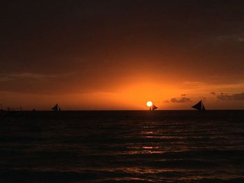 Silhouette of sailboat in sea at sunset