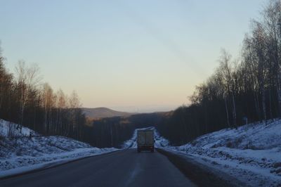 Road amidst trees against sky during winter