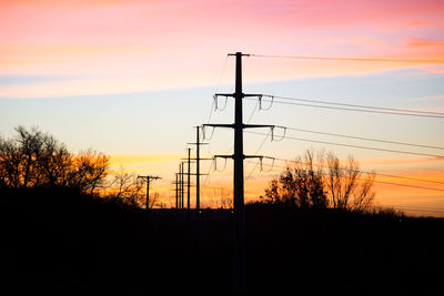 Silhouette electricity pylon against dramatic sky during sunset