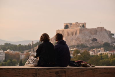 Rear view of man and woman looking at buildings against sky