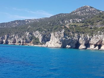 Scenic view of sea and mountains against blue sky