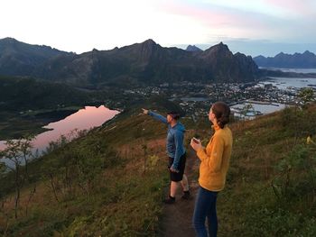 Full length of friends standing on mountain against sky