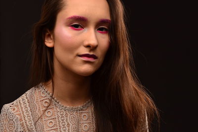 Close-up portrait of beautiful young woman over black background