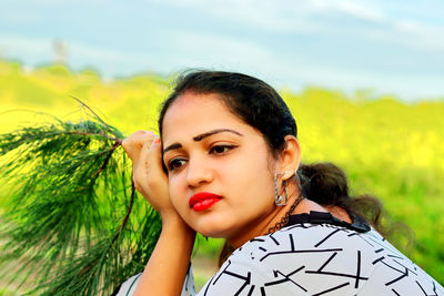 A gorgeous indian young woman closeup face view and holding the tree branch in hand thinking somethi