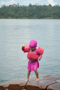 Full length of cute girl standing by lake