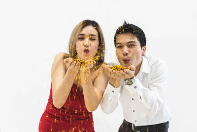 Young man eating food against white background
