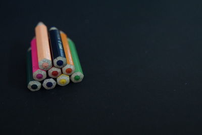 Close-up of colored pencils on table against black background