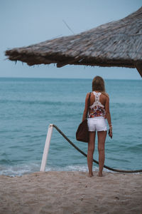 Rear view of woman standing at beach