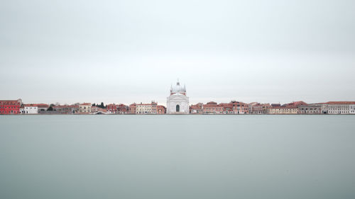 View of river by buildings against sky