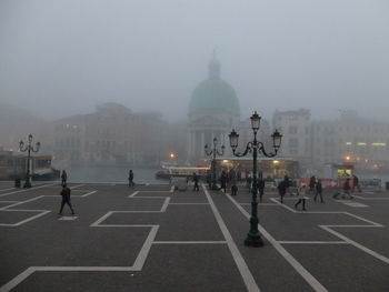 People in city against sky during foggy weather