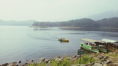 Boat sailing in river against sky during foggy weather