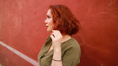 Redhead young woman standing against wall