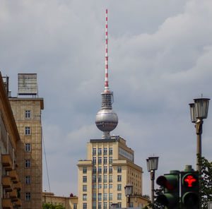 Communications tower in city against sky