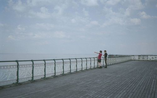 People standing on pier over sea against sky