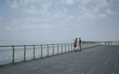 People standing on pier over sea against sky