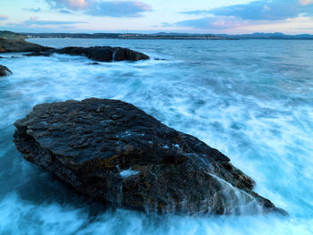 Rock formation on sea shore against sky