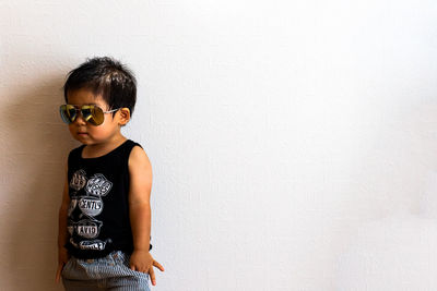 Man looking away while standing against wall