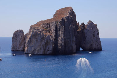 Rock formations by sea against clear sky