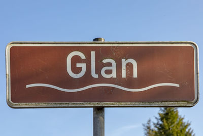 Low angle view of road sign against clear blue sky