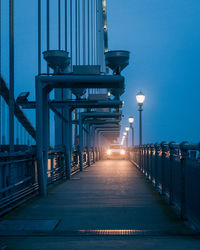 Illuminated street lights against clear blue sky at dusk