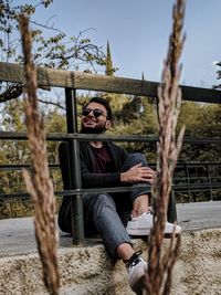 Portrait of young man sitting by tree