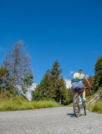 Rear view of man riding bicycle on road