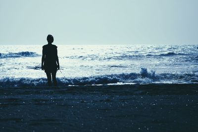 Silhouette man standing on beach against clear sky