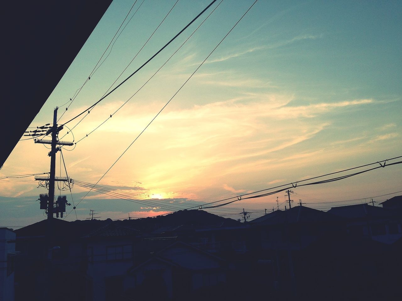 sunset, silhouette, built structure, power line, architecture, low angle view, building exterior, sky, electricity pylon, orange color, electricity, cable, power supply, house, connection, fuel and power generation, outdoors, dusk, residential structure, no people