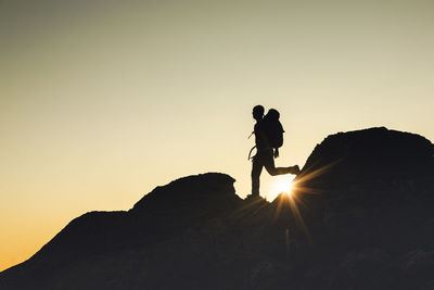 Man silhouette over a rock at sunset