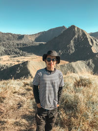 Portrait of man wearing sunglasses standing against mountain