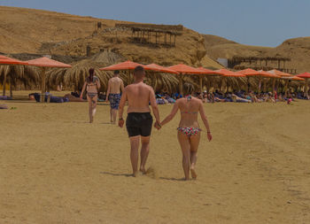 Rear view of people at beach against sky