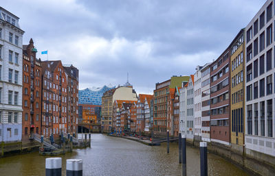 Canal amidst buildings in city against sky