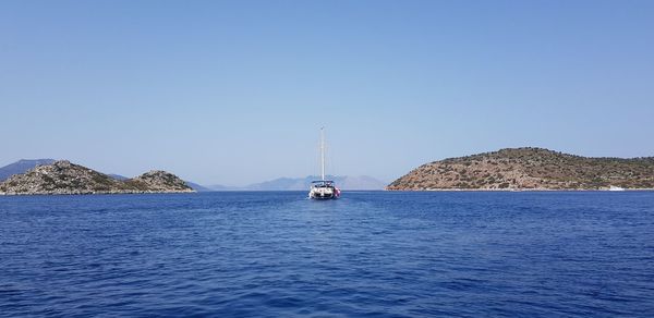 Sailboats sailing in sea against clear blue sky