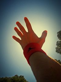 Low angle view of cropped hand against sky