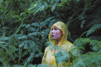 Woman in raincoat standing against plants