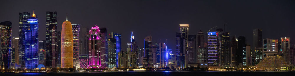 Illuminated modern buildings against sky at night