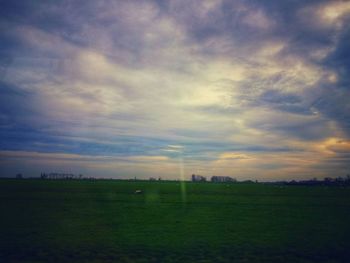 Scenic view of grassy field against cloudy sky