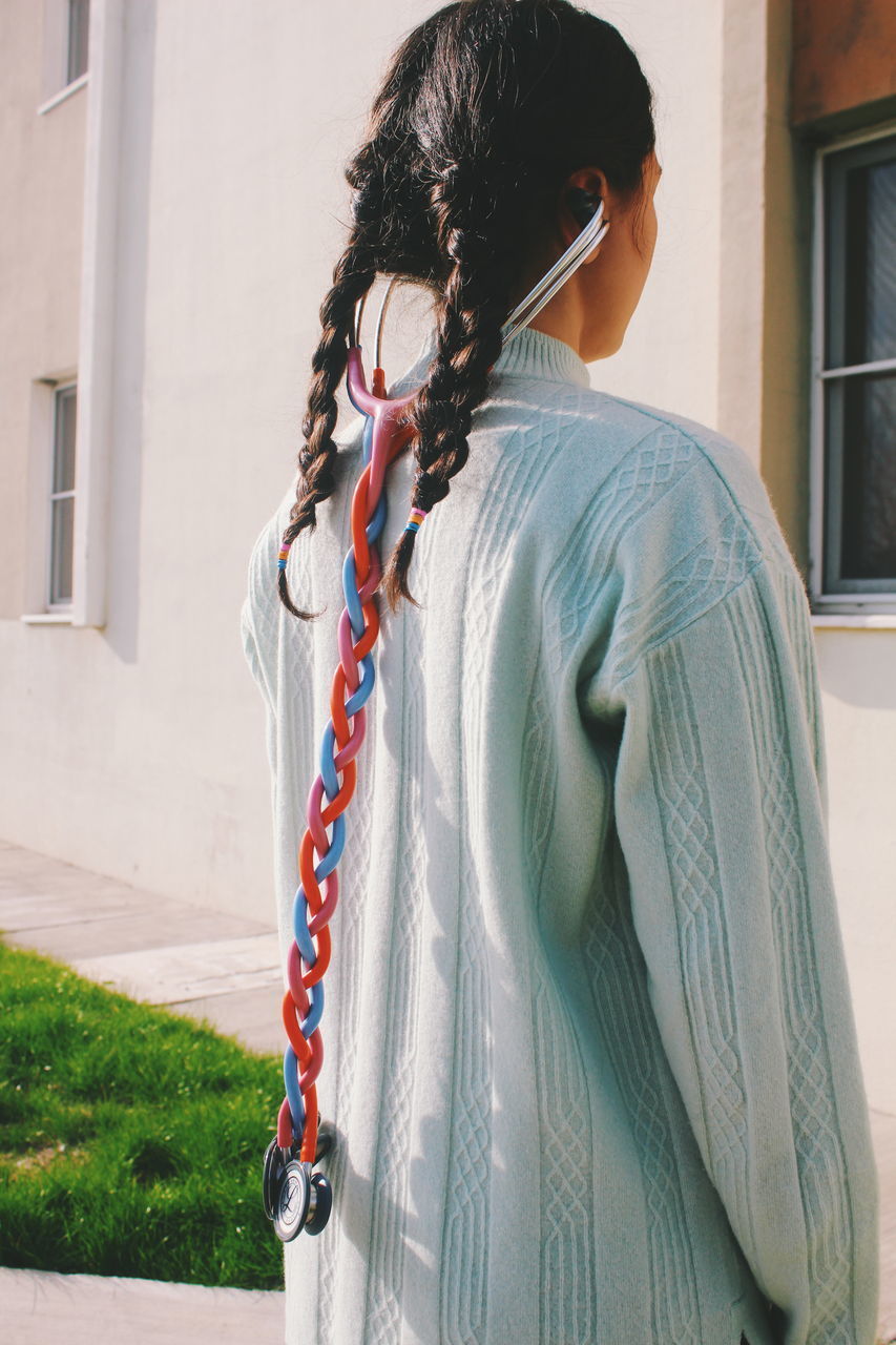 Rear view of woman with braided hair and stethoscope outdoors