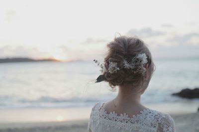 Rear view of bride wearing flowers at beach