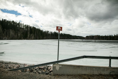 Road sign on snow covered landscape against sky