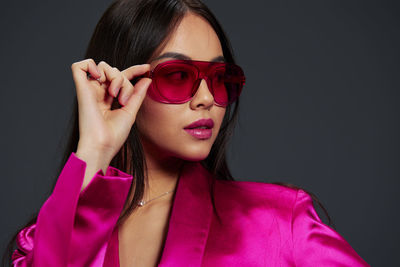 Portrait of young woman wearing sunglasses against black background