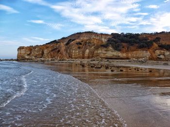 Scenic view of rocky coastline against cloudy sky