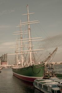 Sailboats moored at harbor against sky