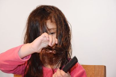 Girl combing hair against wall at home