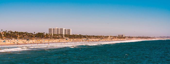 Scenic view of beach by buildings against clear sky