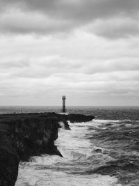 Lighthouse by sea against sky