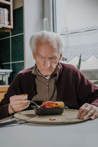 Senior man eating food at home