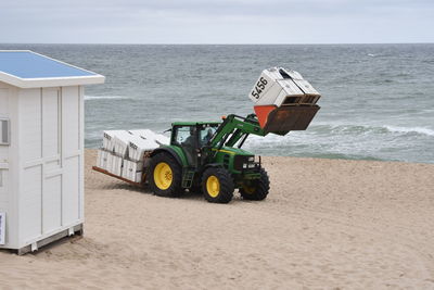 Deck chairs on beach against sky